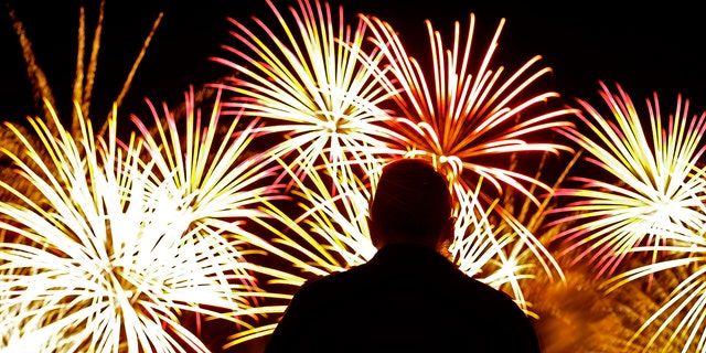 A man watches fireworks after a baseball game between the Kansas City Royals and the Cleveland Indians on Wednesday, July 3, 2019, in Kansas City, Mo., the day before the Fourth of July. Cleveland won 4-0. (AP Photo/Charlie Riedel)