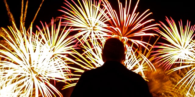 A man watches fireworks after a baseball game between the Kansas City Royals and the Cleveland Indians on Wednesday, July 3, 2019, in Kansas City, Mo., the day before the Fourth of July. Cleveland won 4-0. (AP Photo/Charlie Riedel)
