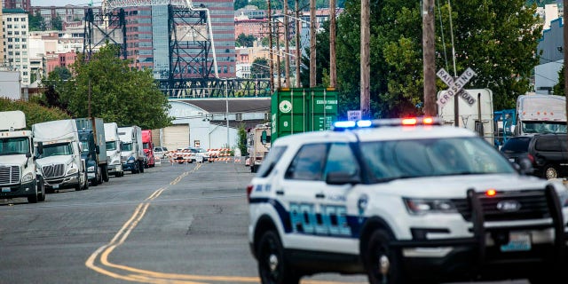 A police officer guards the front of a road block near the Northwest Detention Center Saturday in Tacoma, Wash. after a man armed with a rifle threw incendiary devices at the facility.
