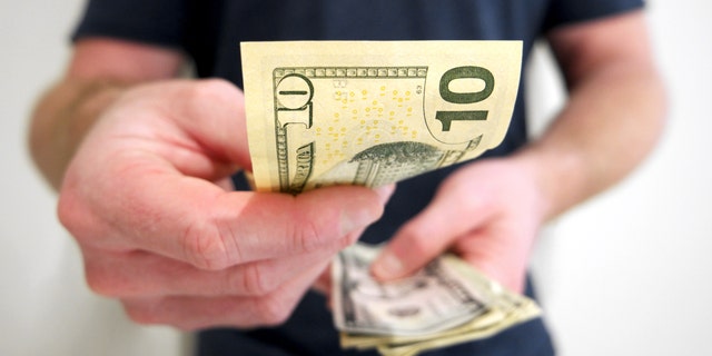 A man handing out american ten dollar bill. A picture that describes buying, paying, handing out money, or showing money.