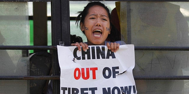 In this March 10, 2015 photo, a Tibetan exile shouts slogans against China after being detained inside a police bus during a protest in New Delhi, India. (AP Photo/Altaf Qadri, File)