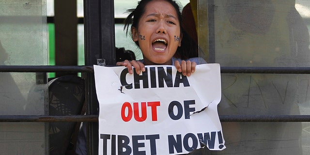 In this March 10, 2015 photo, a Tibetan exile shouts slogans against China after being detained inside a police bus during a protest in New Delhi, India. (AP Photo/Altaf Qadri, File)