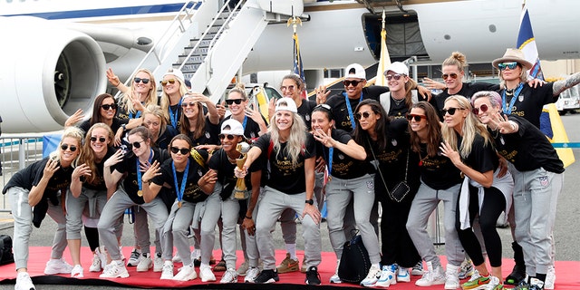 The U.S. women's soccer team posing with the World Cup trophy after arriving at Newark Liberty International Airport on Monday.