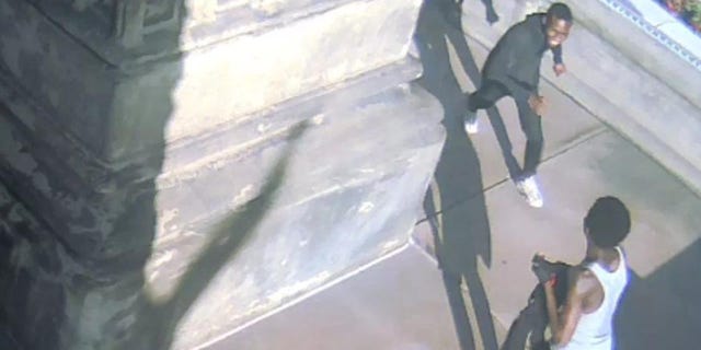 Two men are seen around the base of the Soldiers' and Sailors' Monument in Cleveland on Wednesday evening. (Surveillance video)