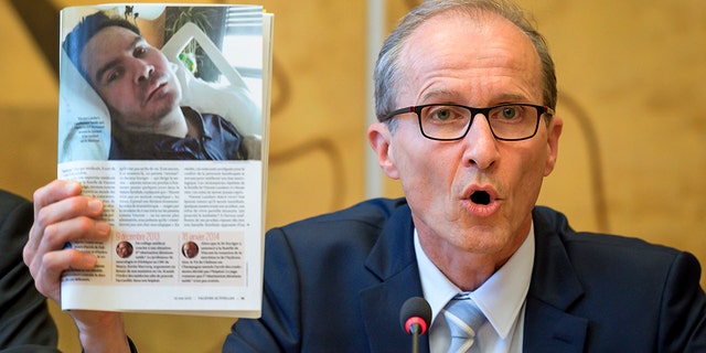 Neurologist and advisor of Vincent Lamber's parent shows a picture of Vincent Lambert who had been is in a vegetative state since 2008, during an event on the sideline of the United Nations Human Rights Council in Geneva on July 1, 2019.