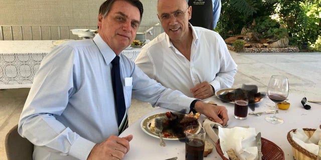 Smudged black crosses attempt to hide what Israeli ambassador Yossi Shelley, right, and Brazilian President Jair Bolsonaro, left, were eating at lunch in Brasilia Sunday. (Israeli embassy in Brazil)