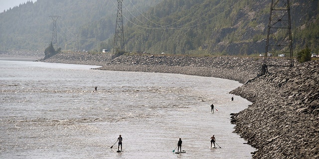 ANCHORAGE, AK - JULY 04: People navigate the Turnagain Arm on paddle boards as vehicles move along the Seward Highway on July 4, 2019 south of Anchorage, Alaska. Alaska is bracing for record warm temperatures and dry conditions in parts of the state. (Photo by Lance King/Getty Images)