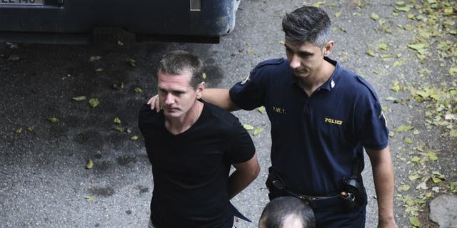 A Russian man identified as Alexander Vinnik, left, is escorted by police officers as he arrives to the courthouse at the northern Greek city of Thessaloniki on Wednesday, Oct. 4, 2017. (Associated Press)