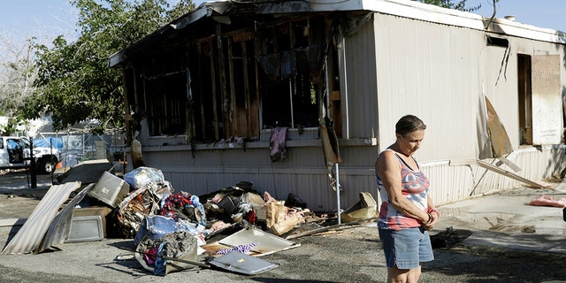 Katherine Johnson-Coates stands outside of a neighbor's burned down mobile home in the aftermath of an earthquake in Ridgecrest, Calif. Crews in Southern California assessed damage to cracked and burned buildings, broken roads, leaking water and gas lines and other infrastructure Saturday after the largest earthquake the region has seen in nearly 20 years jolted an area from Sacramento to Las Vegas to Mexico. (AP Photo/Marcio Jose Sanchez)