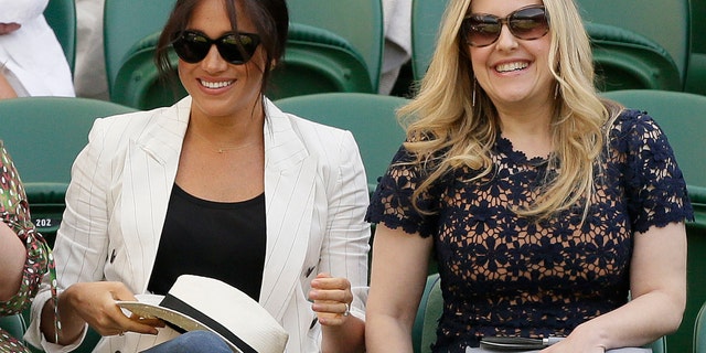 Meghan, Duchess of Sussex, left, smiles as she takes her seat on Court Number One to watch United States' Serena Williams play Slovenia's Kaja Juvan in a singles match during day four of the Wimbledon Tennis Championships. (AP Photo/Tim Ireland)