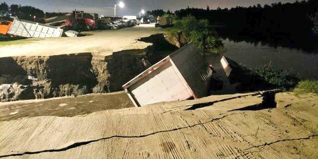 Officials are investigating if the trucks fell into a sinkhole or if the fracture in the ground was caused by something else.