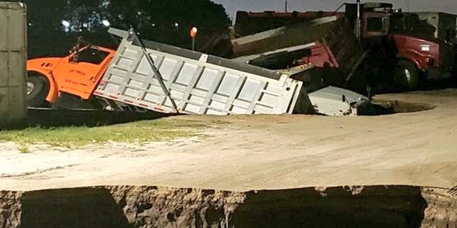 Trucks can be seen sticking out of a possible sinkhole in Florida early Wednesday.