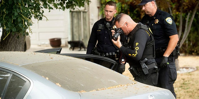 A police officer photographs a car outside the family home of Gilroy Garlic Festival gunman Santino William Legan on Monday. (AP)