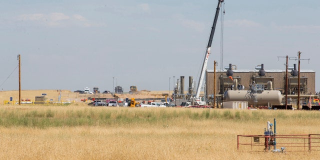 In this photo taken Wednesday, July 24, 2019, authorities investigate the scene in the distance after oilfield workers discovered bones in rural Weld County in northern Colorado. (Michael Brian/Greeley Tribune via AP)