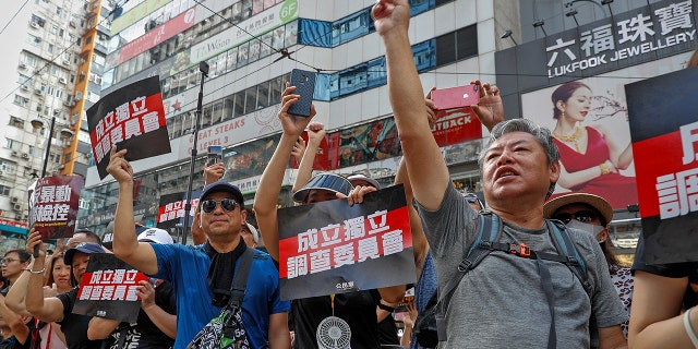 Protesters gesture while holding placards reads "Form an independent investigation on legislative committee" during a march in Hong Kong, Sunday, July 21, 2019. Thousands of Hong Kong protesters marched from a public park to call for an independent investigation into police tactics.(AP Photo/Vincent Yu)