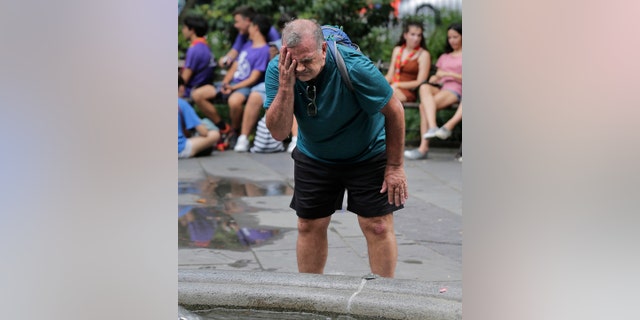 Russ Wilson splashes water on his face from a fountain in New York, Wednesday, July 17, 2019. (AP Photo/Seth Wenig)