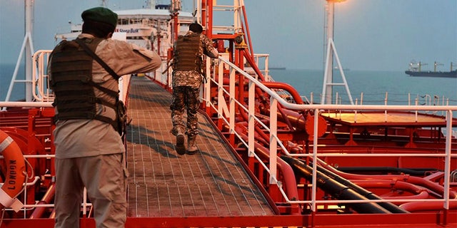 Two armed members of Iran's Revolutionary Guard inspect the British-flagged oil tanker Stena Impero, which was seized in the Strait of Hormuz on Friday by the Guard, in the Iranian port of Bandar Abbas. (AP/Mehr News Agency)