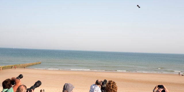 People watch as Franky Zapata, a 40-year-old inventor, takes to the air in Sangatte, Northern France, at the start of his attempt to cross the channel from France to England on July 25, 2019.