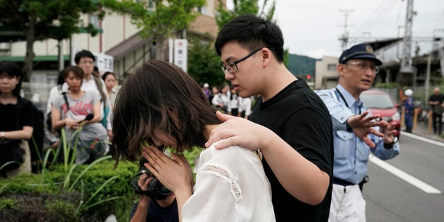 A woman prays to honor the victims of Thursday's fire at the Kyoto Animation Studio building, Friday, July 19, 2019, in Kyoto, Japan. A man screaming "You die!" burst into the animation studio in Kyoto, doused it with a flammable liquid and set it on fire Thursday, killing dozens of people in the attack that shocked the country and brought an outpouring of grief from anime fans. (AP Photo/Jae C. Hong)