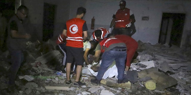 Libyan Red Crescent workers recover migrants bodies after an airstrike at a detention center in Tajoura, east of Tripoli on Wednesday.