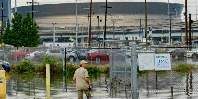 Frank Conforto Jr. walks in the parking lot of the University Medical Center (UMC) with the Mercedes-Benz Superdome in the background on Glavez Street in New Orleans after flooding from a storm Wednesday, July 10, 2019.