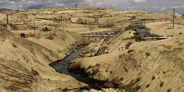 In this May 10, 2019 photo provided by California's Office of Spill Prevention and Spill Response, oil is flowing into a Chevron oil field in Kern County, California. Nearly 800,000 gallons of oil and water have been flowing from the ground since May. (Office of Spill Prevention and Spill Response via the California Department of Fish and Wildlife)