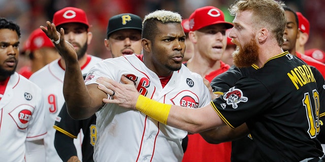 Cincinnati Reds' Yasiel Puig (66) is restrained by Pittsburgh Pirates third baseman Colin Moran (19) during the ninth inning of a baseball game Tuesday, July 30, 2019, in Cincinnati. (Associated Press)