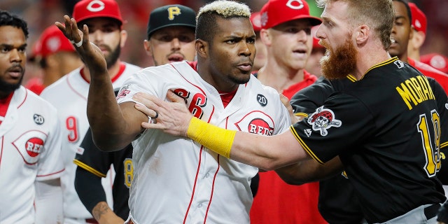 Cincinnati Reds' Yasiel Puig (66) is restrained by Pittsburgh Pirates third baseman Colin Moran (19) during the ninth inning of a baseball game Tuesday, July 30, 2019, in Cincinnati. (Associated Press)