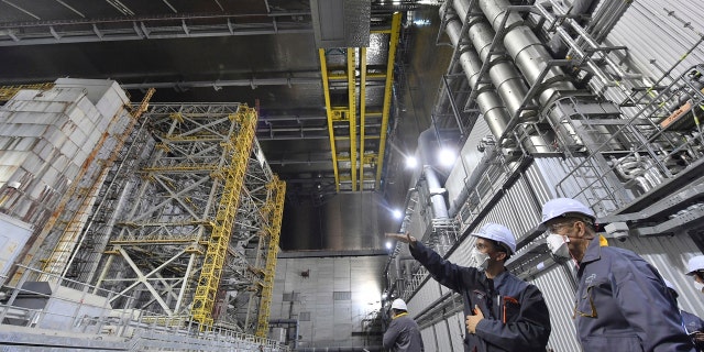 In this June 1, 2019, file photo, French Foreign Minister Jean-Yves Le Drian, right, listens to an employee inside the New Safe Confinement (NSC) movable enclosure at the nuclear power plant in Chernobyl, Ukraine. A new structure built to confine the Chernobyl reactor at the center of the world's worst nuclear disaster was previewed for the media Tuesday, July 2. (Sergei Supinsky/Pool Photo via AP, File)