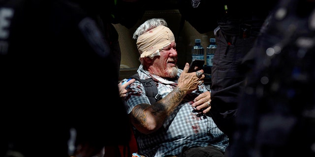 A man checks his phone while surrounded by police and medics after being injured during a civil disturbance in Portland, Ore., on Saturday, June 29, 2019. (Associated Press)