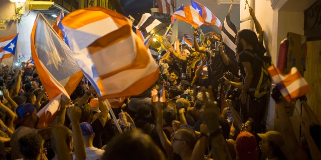 People celebrate outside the governor's mansion La Fortaleza, after Gov. Ricardo Rossello announced that he is resigning. (AP Photo/Dennis M. Rivera Pichardo)