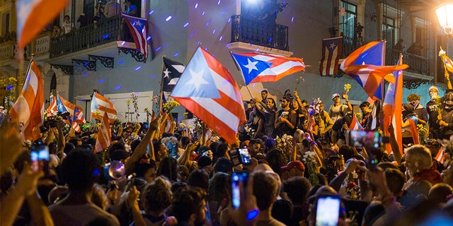 People celebrate outside the governor's mansion after Ricardo Rossello announced that he is resigning Aug. 2 after nearly two weeks of protests and political upheaval touched off by a leak of crude and insulting chat messages between him and his top advisers.