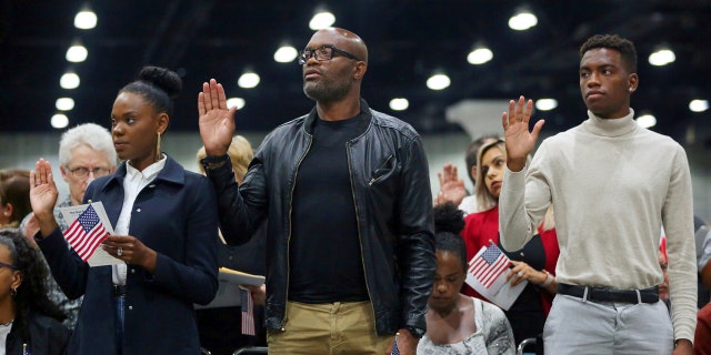 Mixed martial arts great Anderson "Spider" Silva of Brazil, center, his daughter Kaory, 23, left, and son Kalyl, 20, are is sworn in as a U.S. citizen along with thousands of others in a mass naturalization ceremony Tuesday, July 23, 2019 at the Los Angeles Convention Center. (AP Photo/Reed Saxon)