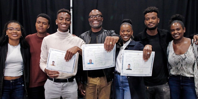 Mixed martial arts great Anderson "Spider" Silva of Brazil, center, his daughter Kaory, 23, right, and son Kalyl, 20, left, hold their citizenship documents after they are sworn in as U.S. citizens in a mass naturalization ceremony Tuesday, July 23, 2019 at the Los Angeles Convention Center. Joining them are family members who are not yet citizens, from left, daughter Kauana, 18; Joao, 14; and son Gabriel, 22, and Anderson Silva's wife Dayane. (AP Photo/Reed Saxon)