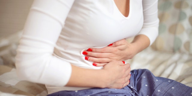 Young woman clutches her stomach.