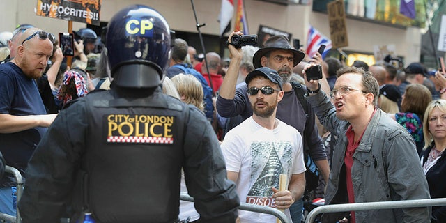 Police in riot gear watch Tommy Robinson supporters outside the Old Bailey courthouse in London on Thursday (AP/PA)