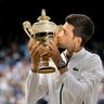 Serbia's Novak Djokovic kisses the trophy after defeating Roger Federer in the men's singles final at the Wimbledon Tennis Championships in London, July 14, 2019. 