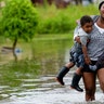 Terrian Jones carries Drew and Chance Furlough during flooding from a storm in the Gulf Mexico in New Orleans, July 10, 2019.