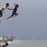Boys jump into the water after a strong downpour at Manila's Bay, Philippines, July 17, 2019. 