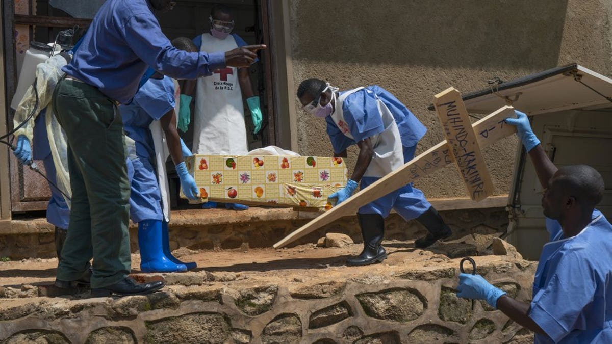 In this Sunday, July 14, 2019 photo, Red Cross workers carry the remains of 16-month-old Muhindo Kakinire from the morgue into a truck as health workers disinfect the area in Beni, Congo. The World Health Organization has declared the Ebola outbreak an international emergency.