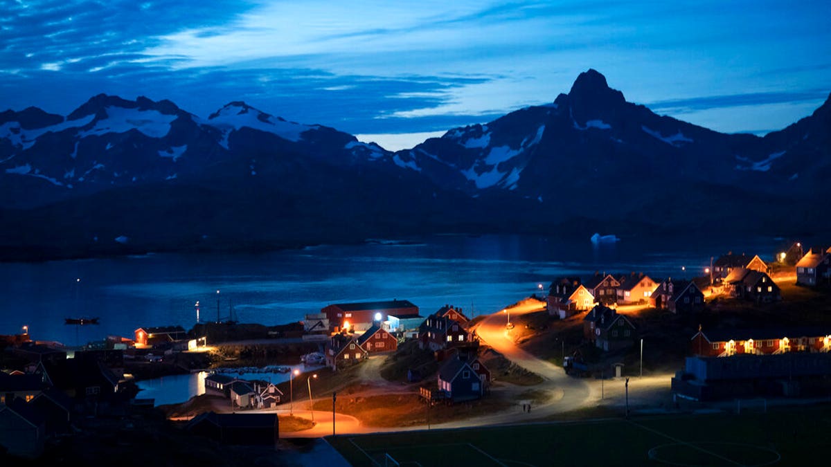 In this photo taken late Friday, Aug. 16, 2019, homes are illuminated after the sunset in Tasiilaq, Greenland. (AP Photo/Felipe Dana)