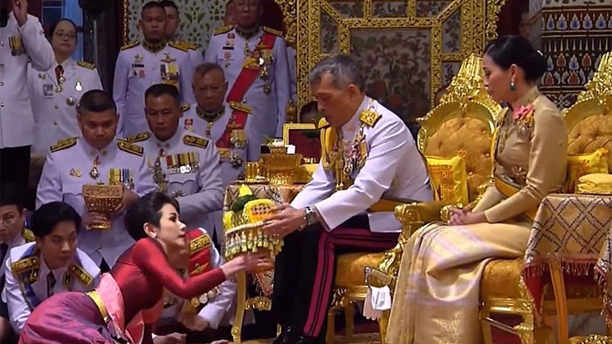 King Maha Vajiralongkorn (center), also known as King Rama X, sits alongside his wife General Suthida Vajiralongkorn (right) as he names Major-General Sineenat Wongvajirapakdi (left) the new Royal Noble Consort.