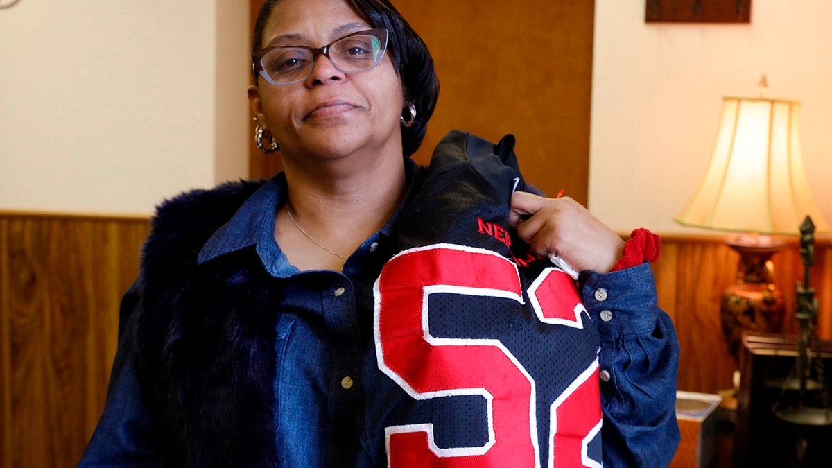 JoAnne Atkins-Ingram drapes her late son's Neptune High School football jersey over her shoulder.  (Doug Hood/The Asbury Park Press via AP File)