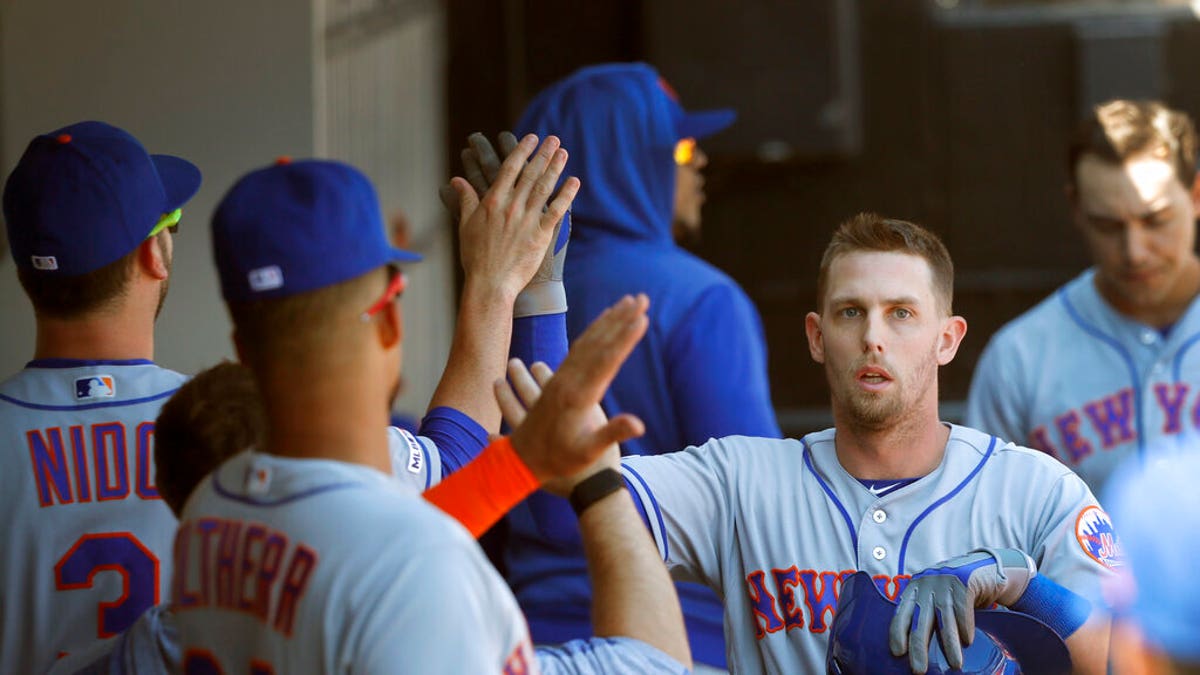 New York Mets' Jeff McNeil, right, celebrates in the dugout after scoring on Robinson Cano's RBI double off Chicago White Sox starting pitcher Dylan Cease, during the sixth inning of a baseball game Thursday, Aug. 1, 2019.