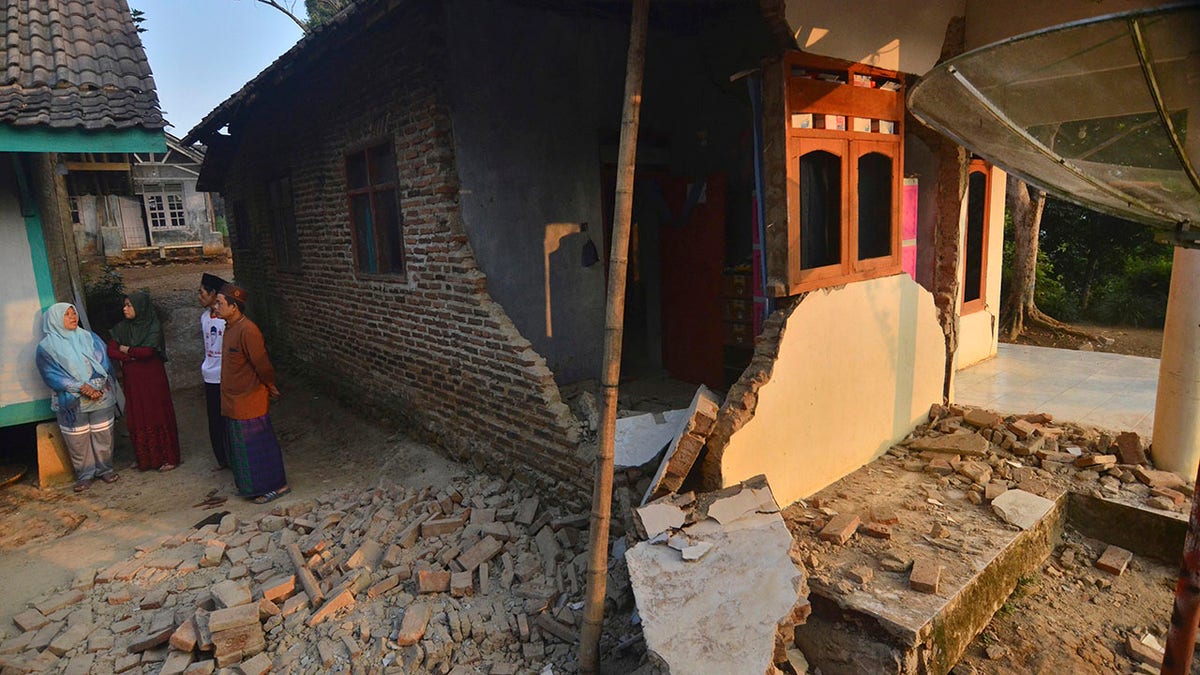 Residents talk near a house damaged in an earthquake in Mandalawangi, Banten province, Indonesia, Saturday, Aug. 3, 2019. (Associated Press)