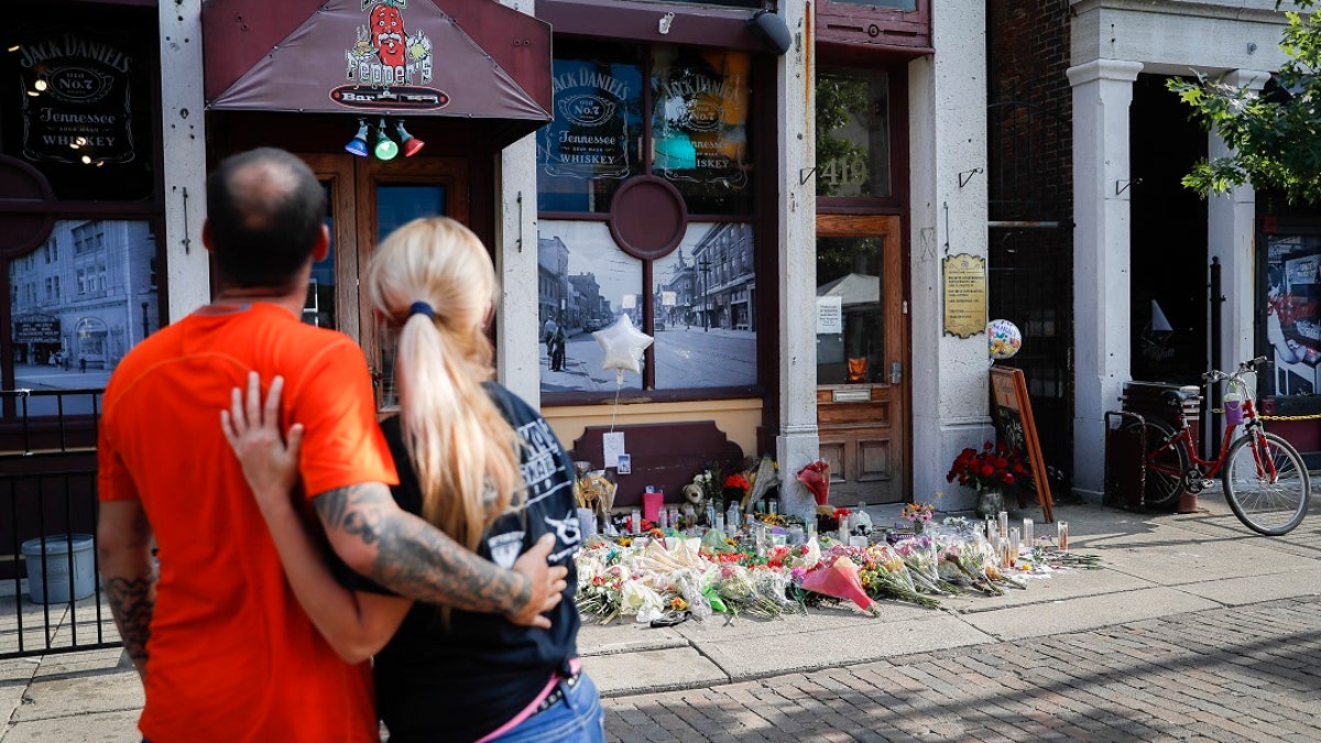 Mourners pause at a makeshift memorial for the slain and injured outside Ned Peppers bar in the Oregon District after a mass shooting in Dayton, Ohio. 