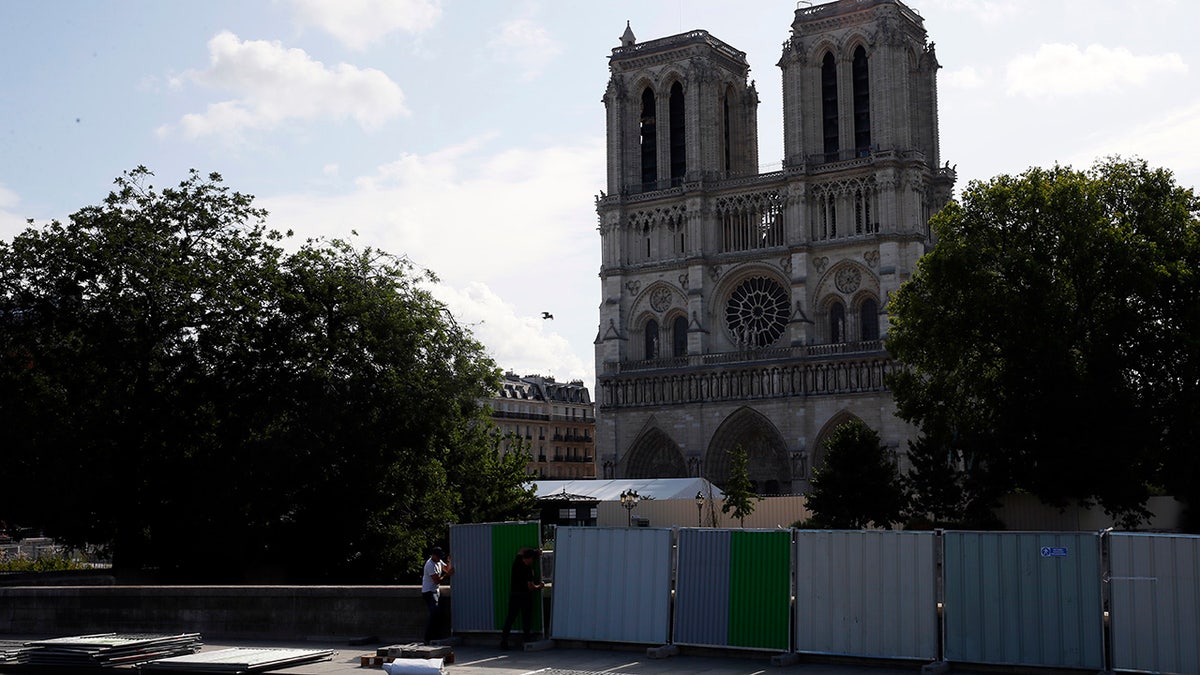 Workers install high fences on a bridge around Notre Dame cathedral in Paris, Tuesday, Aug. 13, 2019. Workers are preparing to decontaminate some Paris streets surrounding the Notre Dame Cathedral that have been tested with high levels of lead following the April blaze that damaged the landmark.