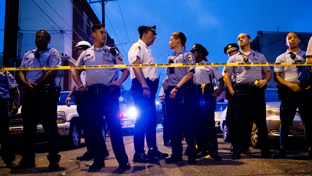 Officers gather for crowd control near a massive police presence set up outside a house as they investigate a shooting in Philadelphia, Wednesday, Aug. 14, 2019. (Associated Press)