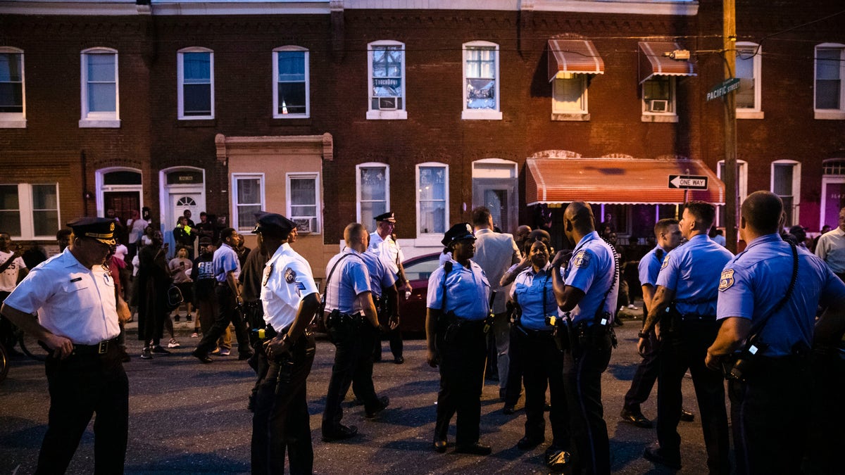 Officers gather for crowd control near a massive police presence set up outside a house as they investigate an active shooting situation, in Philadelphia, Wednesday, Aug. 14, 2019. (Associated Press)