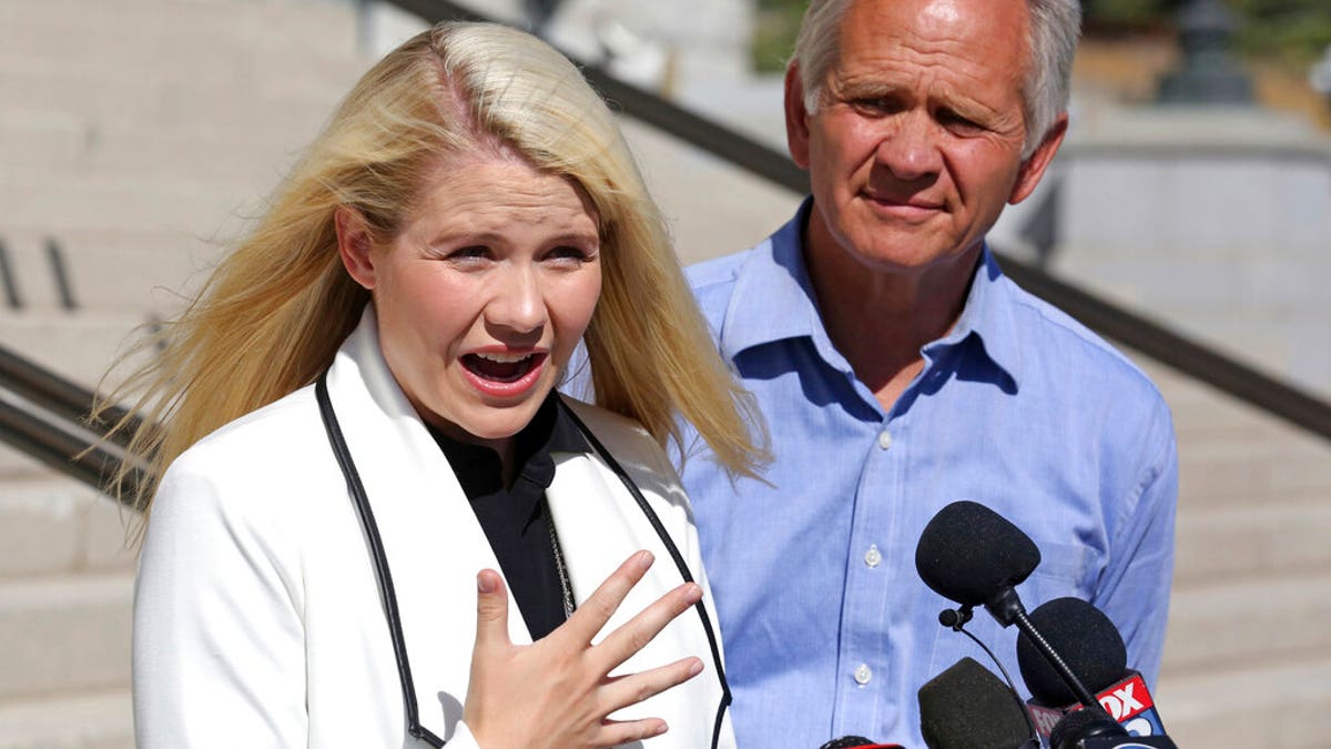 Elizabeth Smart speaks during a news conference while her father Ed Smart looks on, in Salt Lake City.